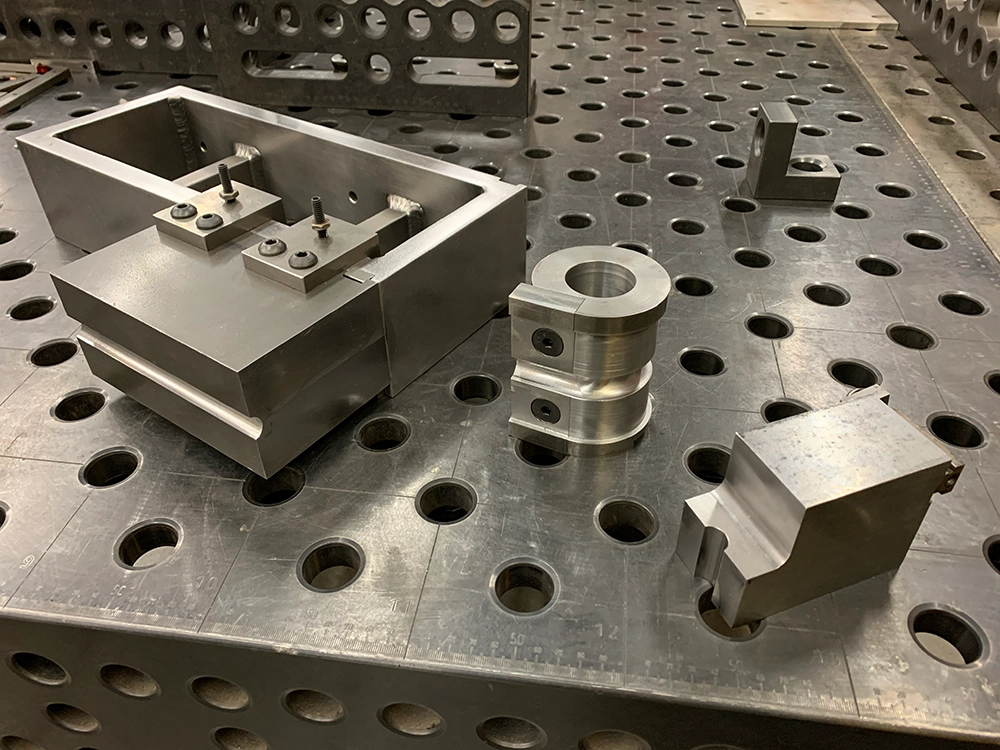 Engineer TIG welding a tube chassis using CNC machined fixtures for alignment